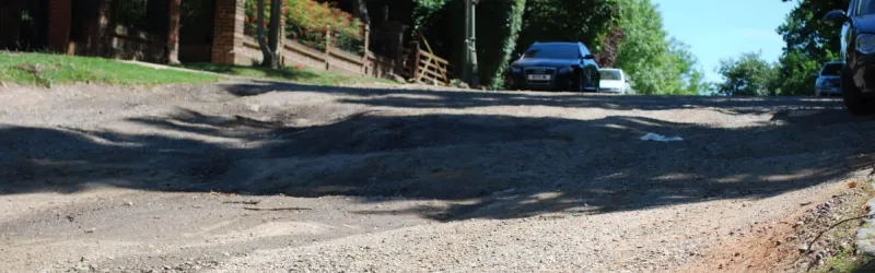 Deep craters in the surface of an unadopted road. Mind your step! Click to enlarge