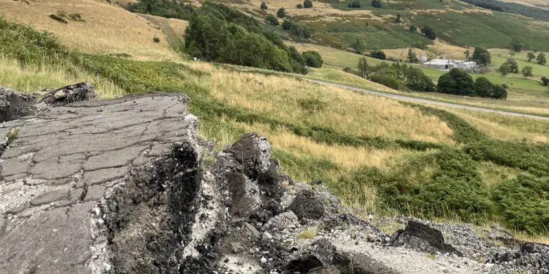 A view down the hill, with a broken road in the foreground. Click to enlarge