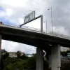 As the viaducts part, a second gantry supplies local directions for the approaching interchange. The right hand sign incorporates a Give Way warning - the first sign of the unusual road layout ahead.