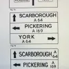 Using a sign of exactly the same dimensions, this example shows how stacking destinations is more efficient on space; in the bottom example the road numbers are split across two lines to maximise space usage even more.