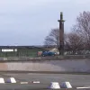 Marooned on a grass verge, and rather inaccessible amid the various flyovers, underpasses and marshalling areas, is the monument placed at the tunnel mouth at its opening in 1934. In the foreground the southern marshalling area is visible; the white concrete blocks originally protected the supports for overhead signal gantries for the failed traffic control system.