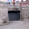 The tunnel mouth itself, with another elaborate carving. Apart from one CCTV camera and the barbed wire placed around the top by the owners of neighbouring property, this entrance seems to have survived in much better condition than the three that are still in use. Behind the heavy gates there is a light turned on which suggests the tunnel is still actively used.