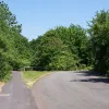 Not much chance to take advantage of the well-engineered road though: the road turns another corner and then stops. There are two old lines here; through the trees is Oakwood Gate junction on Birchwood Way and the road curving around to the right is a temporary diversion linking this section of Warrington Road to the new A574 while Birchwood Way was under construction. The gate in the middle is the original course of the road. Today the footpath goes uphill to the left to cross Birchwood Park Avenue on a fo
