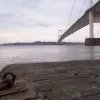 A single mooring hook remains on the slipway. Over the river, the buildings at the former Severn View services are visible.