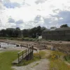 A little way south to Three Locks, near to Bingley town centre. This is where the canal joins in the route too. To the left is visible the retaining wall that supports the newly redirected canal, making space on the right for what is presently a very wide dirt track.