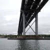 Down below, the two towers are surprisingly insubstantial, considering the enormous weight they carry, rising from caissons sunk into the river bed. Daylight can be seen through the bridge deck.