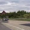 Meanwhile, traffic exiting the M621 eastbound (coming from the M62) has a simple left-hand exit which crosses the railway and comes to these traffic signals. Traffic coming around the swooping gyratory reaches the same junction from the right hand side. Ahead, the grassy bank is a man-made embankment designed to carry the North West Urban Motorway towards the city centre.