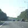 Straight and open again. In order to reduce land-take it avoids cuttings and embankments, instead simply riding out every dip and rise of the land, and making extensive use of retaining walls. The streetlights break at an old emergency crossover point, long since closed.