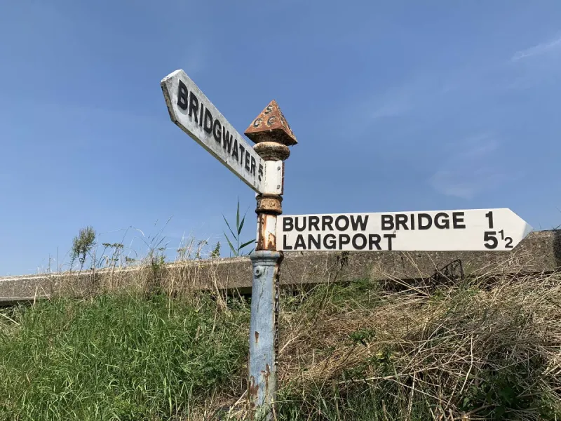 The village of Moorland is also called Northmoor Green, so this can make signposts in and around the charming village in the middle of the levels (at around 5m above sea level!) quite contradictory. This one has an original post and finial, but the arms are later reproductions - written in modern “Transport” lettering, but still cast in metal in the traditional way.